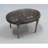 A large silver embossed model of a table on slende