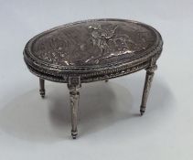 A large silver embossed model of a table on slende