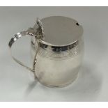 A silver barrel shaped mustard pot with hinged top