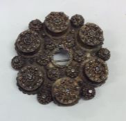 A large circular silver brooch with filigree decor