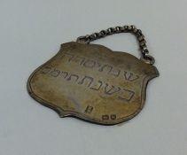 A silver Hebrew shield shaped plaque with suspensi