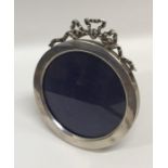 A circular silver picture frame with ribbon top. A