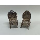 A pair of miniature silver chairs attractively dec