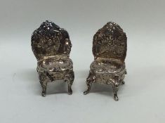 A pair of miniature silver chairs attractively dec