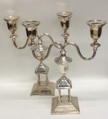 A pair of silver plated candlesticks on stepped ba
