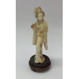 A carved ivory figure of a lady on wooden base. Es
