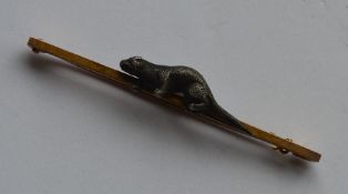 A gold mounted brooch set with an otter on plain b