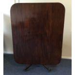 A Georgian mahogany tilt top table on spreading ba