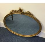 A gilt framed oval wall mirror decorated with a ch