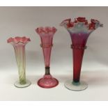 A group of three cranberry glass vases. Est. £25 -