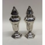 A pair of tall slender silver peppers on hexagonal