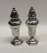 A pair of tall slender silver peppers on hexagonal