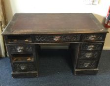An oak carved twin pedestal desk with leather inse
