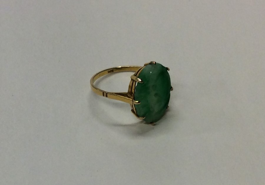A gold and jade single stone ring in claw mount. A