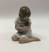 A Royal Copenhagen figure of a child with a baby.