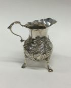 A Georgian silver embossed cream jug decorated wit