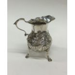A Georgian silver embossed cream jug decorated wit