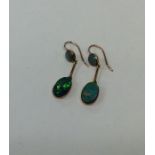 A pair of black opal doublet gold drop earrings. A