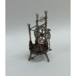 A silver dolls' house model of a spinning wheel on