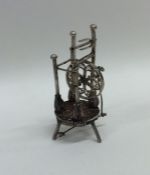 A silver dolls' house model of a spinning wheel on