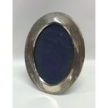 An oval silver picture frame on leather stand. Bir
