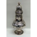 A massive silver caster decorated with swags to li