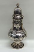 A massive silver caster decorated with swags to li