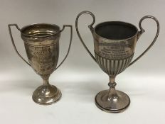 Two silver two handled trophy cups on spreading ba