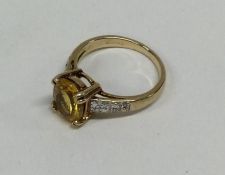 A diamond and yellow stone ring in claw mount. App