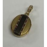 A gold and enamel decorated oval locket with rubie