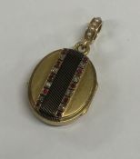 A gold and enamel decorated oval locket with rubie