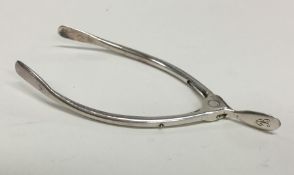 A pair of silver wishbone sugar tongs with spring