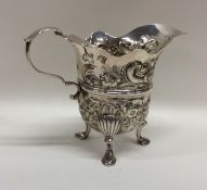 A George II Irish silver cream jug profusely decor
