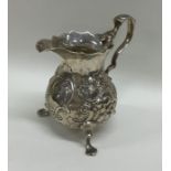 A chased Georgian silver cream jug decorated with