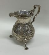 A chased Georgian silver cream jug decorated with