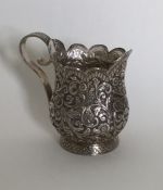A heavy Indian silver cream jug with scroll and le