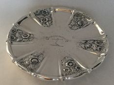 A large circular silver teapot stand attractively