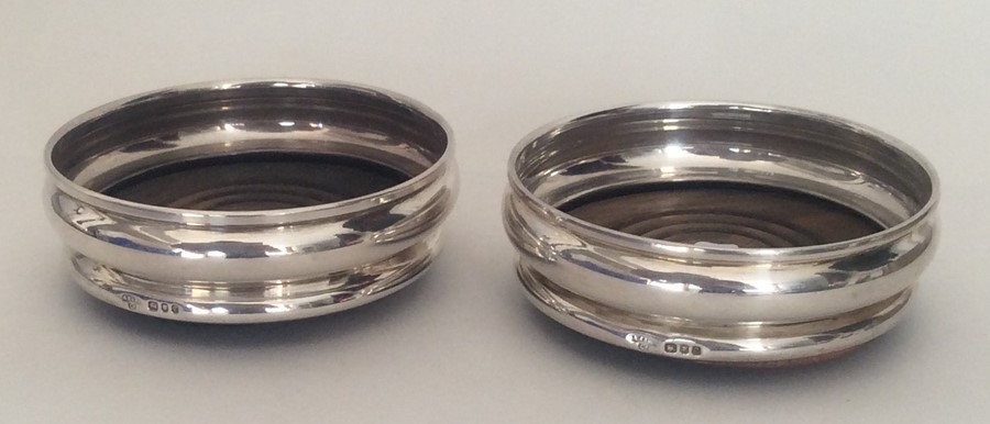 A pair of circular silver mounted bottle coasters.