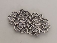 A pierced silver buckle with scroll decoration. Lo