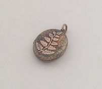 An oval gold locket with leaf decoration to loop t