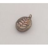 An oval gold locket with leaf decoration to loop t