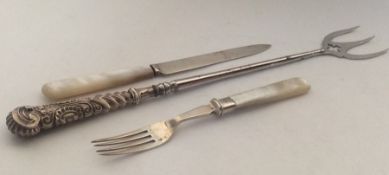 A long silver pickle fork together with a silver k