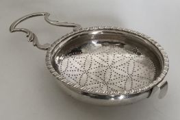 A large silver lemon strainer with pierced bowl an