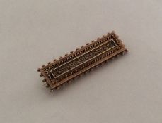 A rectangular 15 carat gold brooch with ball decor