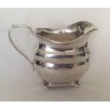 A heavy Edwardian silver panelled cream jug on bal