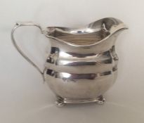 A heavy Edwardian silver panelled cream jug on bal