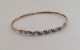 A 9 carat emerald and diamond twist bangle. Approx
