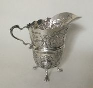 A Georgian style silver embossed cream jug with fl