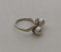 A pearl two stone crossover ring in 14 carat gold.