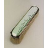 A silver and enamel hairbrush depicting stylish sn